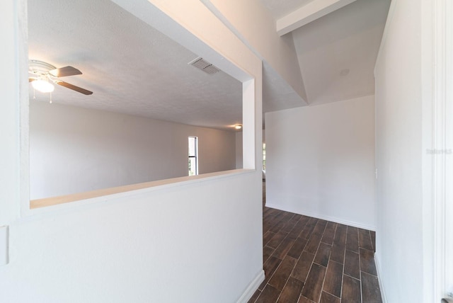 corridor featuring dark wood-style floors, baseboards, and a textured ceiling