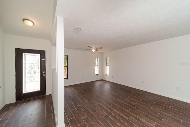 foyer featuring dark wood-style floors, baseboards, ceiling fan, and a textured ceiling