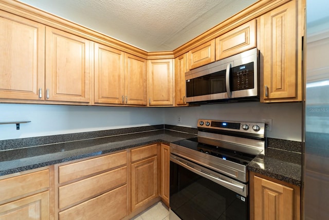 kitchen featuring stainless steel appliances, a textured ceiling, and light tile patterned floors