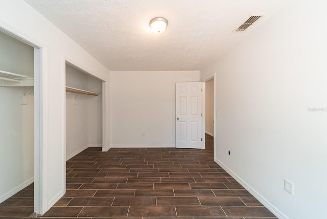 unfurnished bedroom with wood tiled floors, multiple closets, and baseboards