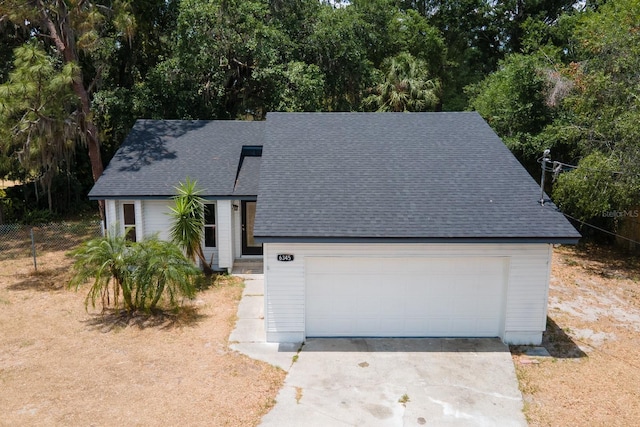 view of front of house with a shingled roof, a garage, fence, and concrete driveway