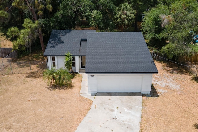 view of front of house featuring fence, roof with shingles, a garage, and concrete driveway