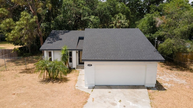 view of front of house with fence, a shingled roof, and concrete driveway