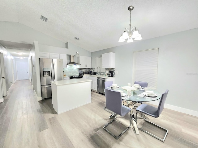 dining area featuring lofted ceiling, a chandelier, light wood-type flooring, a textured ceiling, and baseboards