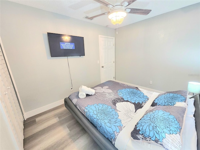 bedroom with wood finished floors, baseboards, and a ceiling fan