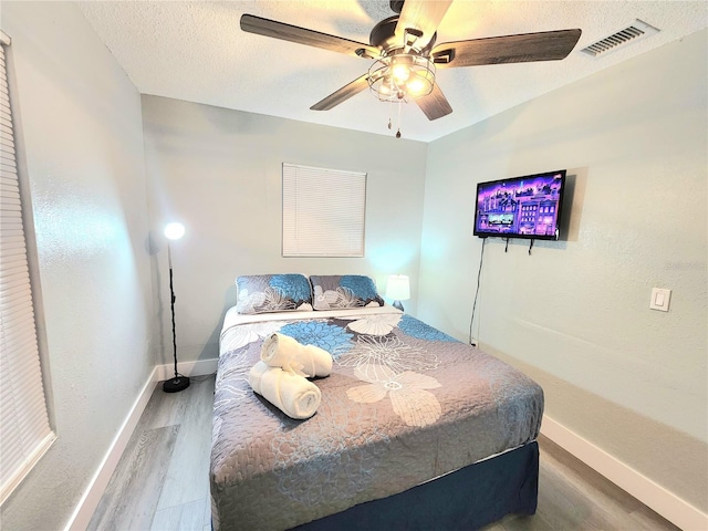 bedroom featuring baseboards, wood finished floors, and ceiling fan