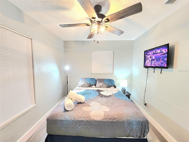 bedroom featuring a textured ceiling, baseboards, and ceiling fan