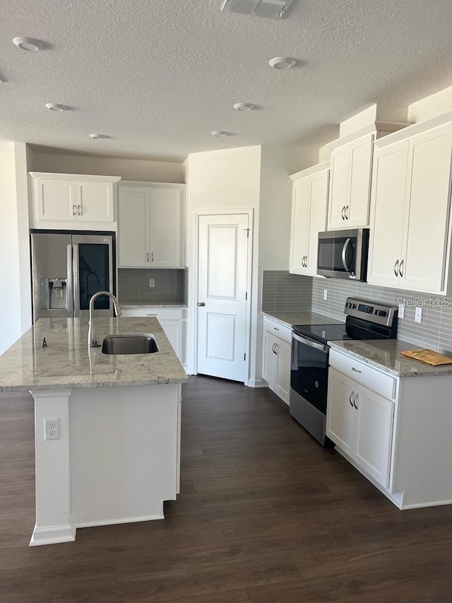 kitchen featuring stainless steel appliances, a sink, white cabinetry, dark wood-style floors, and a textured ceiling
