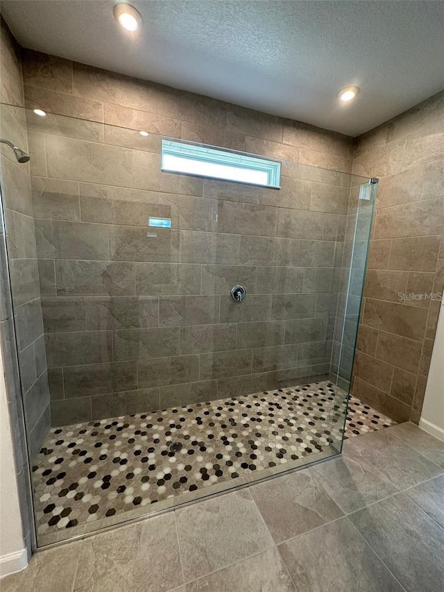 bathroom featuring a walk in shower, a textured ceiling, and recessed lighting