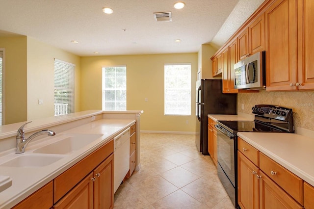 kitchen with stainless steel microwave, black electric range oven, a sink, dishwasher, and backsplash