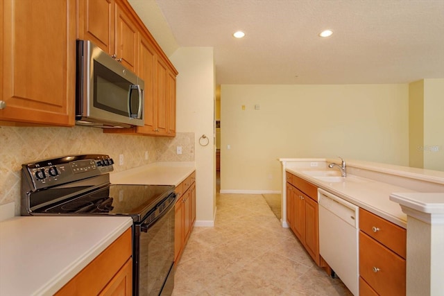 kitchen with electric range, stainless steel microwave, white dishwasher, a sink, and tasteful backsplash