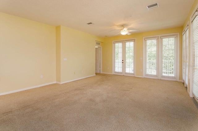empty room with light carpet, a ceiling fan, and baseboards