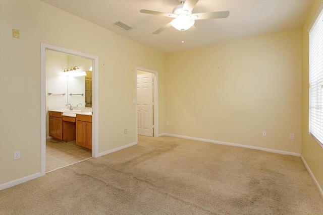 unfurnished bedroom with light colored carpet, baseboards, connected bathroom, and a ceiling fan