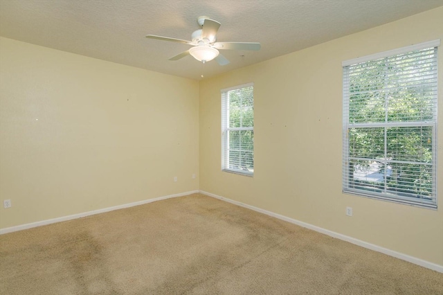 carpeted spare room with a ceiling fan, baseboards, and a textured ceiling