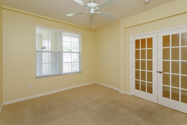 carpeted empty room featuring french doors, a ceiling fan, and baseboards