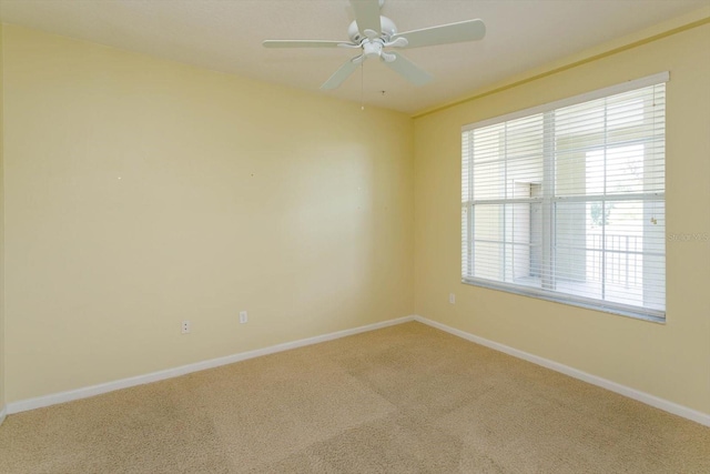 empty room with healthy amount of natural light, carpet floors, baseboards, and a ceiling fan