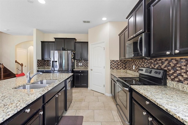 2136 J Lawson Blvd, Orlando, FL 32824 - kitchen with stainless steel appliances, a sink, arched walkways, light stone countertops, and tasteful backsplash