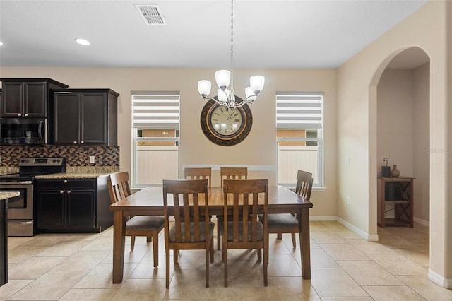 2136 J Lawson Blvd, Orlando, FL 32824 - dining space with arched walkways, a chandelier, light tile patterned floors, baseboards, and recessed lighting