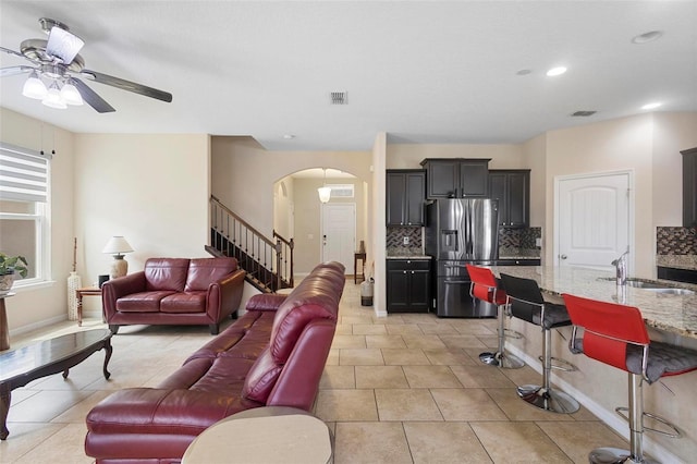 2136 J Lawson Blvd, Orlando, FL 32824 - living area with arched walkways, ceiling fan, stairs, light tile patterned floors, and baseboards