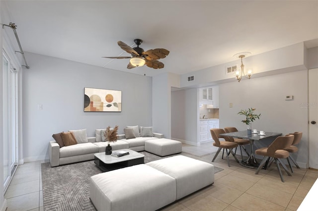 living room with light tile patterned flooring, a chandelier, ceiling fan, and baseboards