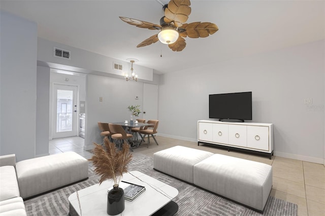 living area featuring a chandelier, ceiling fan, light tile patterned floors, and baseboards
