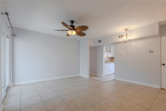 empty room featuring light tile patterned flooring, a chandelier, a ceiling fan, and baseboards