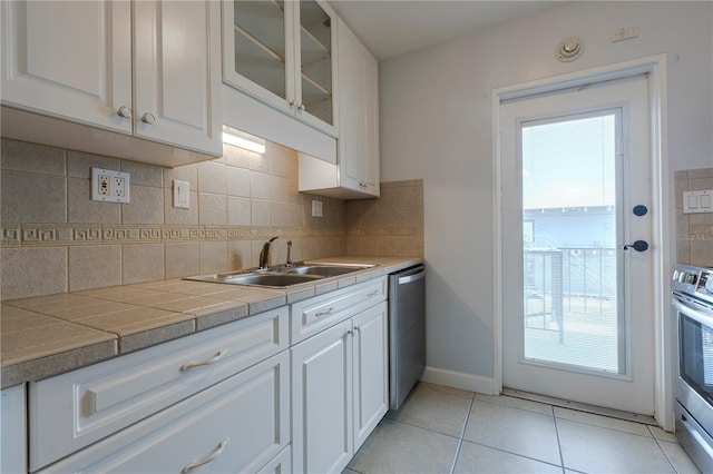 kitchen featuring a sink, stainless steel appliances, white cabinetry, decorative backsplash, and plenty of natural light
