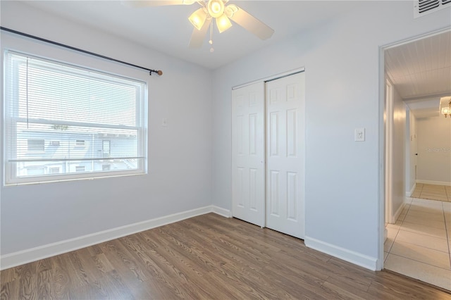 unfurnished bedroom featuring baseboards, wood finished floors, a closet, and a ceiling fan