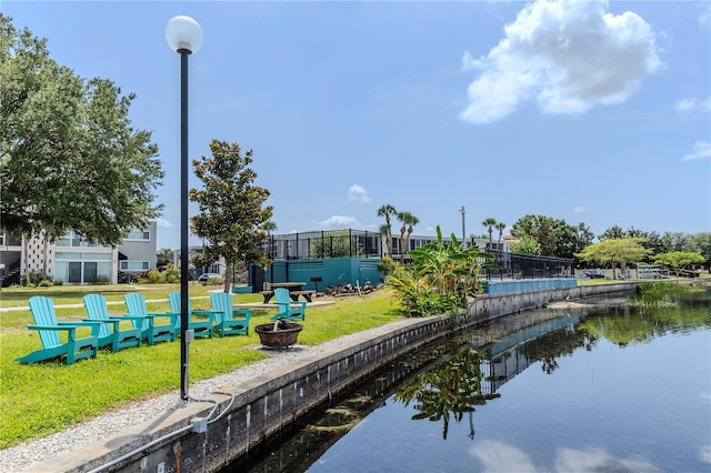 surrounding community with an outdoor fire pit, a yard, and a water view
