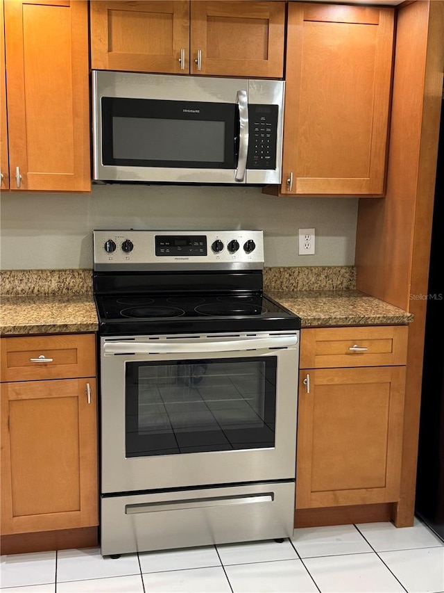14844 Laguna Beach Cir, Orlando, FL 32824 - kitchen with stainless steel appliances, light tile patterned floors, and dark stone countertops