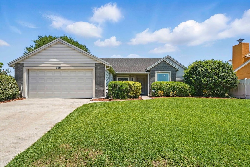 2681 Debany Rd, Kissimmee, FL 34744 - ranch-style home featuring concrete driveway, a garage, a front yard, and brick siding