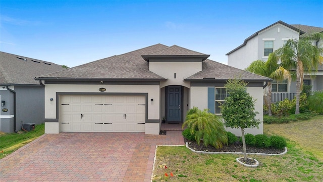 view of front of home with stucco siding, a shingled roof, a garage, and decorative driveway