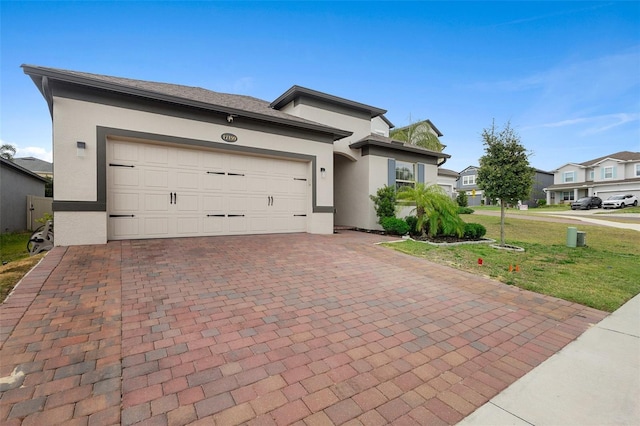 view of front of property with stucco siding, decorative driveway, an attached garage, and a front yard