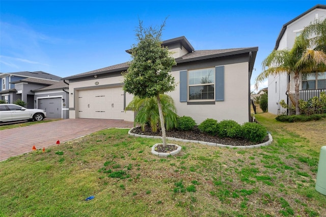 view of front of home with a garage, decorative driveway, stucco siding, and a front yard