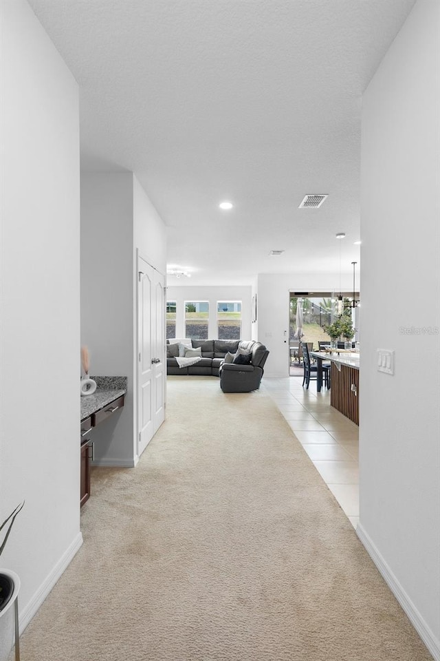 hallway featuring light colored carpet, healthy amount of natural light, baseboards, and recessed lighting