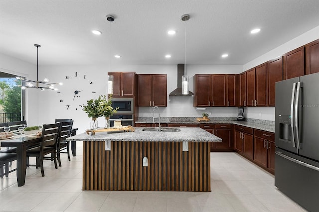 kitchen with appliances with stainless steel finishes, wall chimney range hood, a sink, light stone countertops, and decorative light fixtures