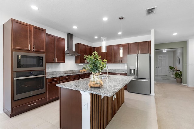 kitchen with appliances with stainless steel finishes, wall chimney range hood, a sink, an island with sink, and recessed lighting