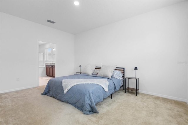 bedroom with light colored carpet, baseboards, recessed lighting, and ensuite bath