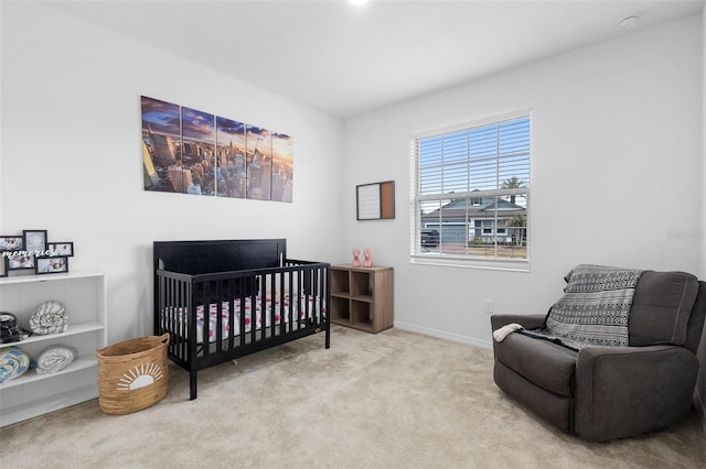 carpeted bedroom featuring baseboards and a crib