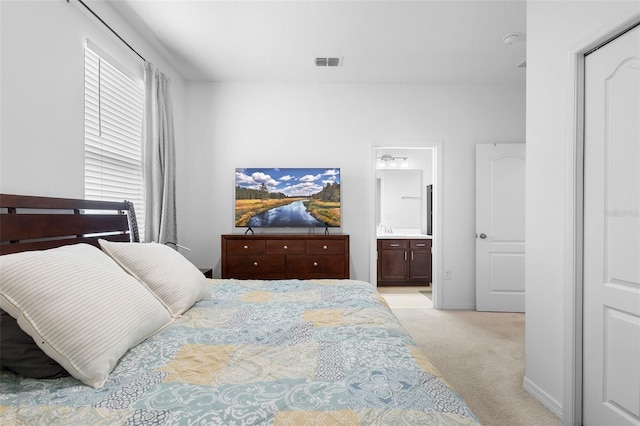 bedroom with light colored carpet and connected bathroom