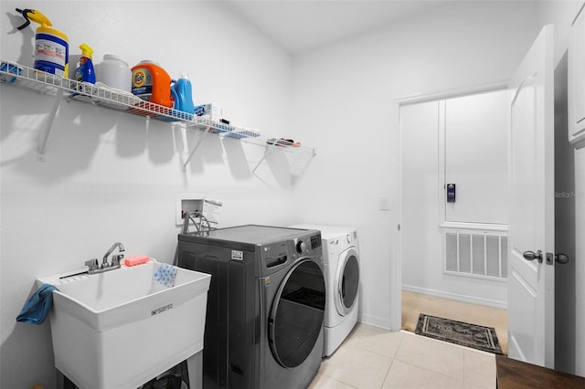 clothes washing area featuring independent washer and dryer, light tile patterned floors, and baseboards