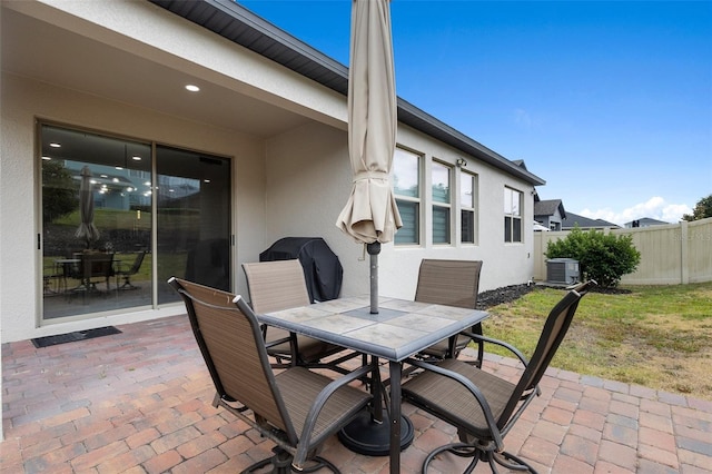 view of patio featuring outdoor dining space, fence, cooling unit, and a grill