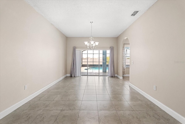 unfurnished dining area featuring a chandelier, arched walkways, a textured ceiling, and baseboards