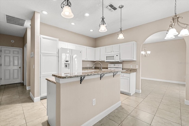 kitchen with white appliances, a chandelier, light stone countertops, white cabinets, and light tile patterned floors