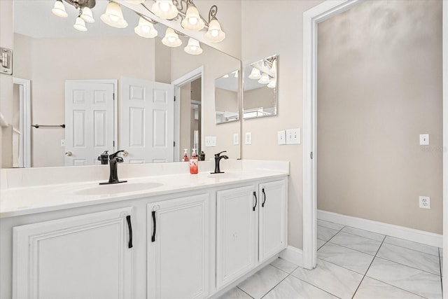 full bathroom with a chandelier, marble look tiles, double vanity, and baseboards