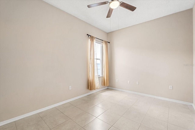 spare room featuring a ceiling fan, baseboards, and light tile patterned flooring