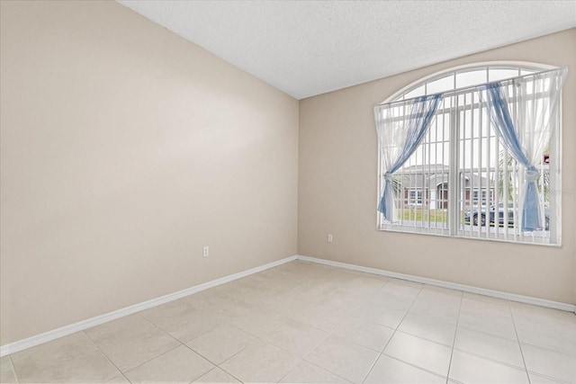 spare room with plenty of natural light, a textured ceiling, baseboards, and lofted ceiling
