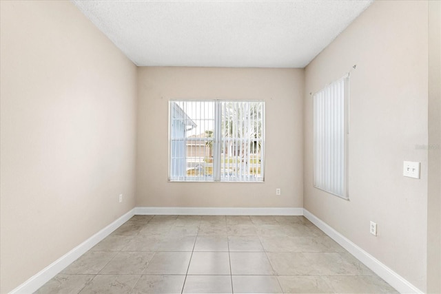 spare room with a textured ceiling and baseboards