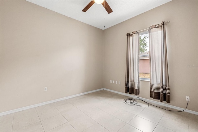 tiled empty room with a ceiling fan and baseboards
