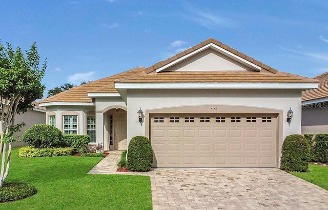 view of front of home featuring stucco siding, a front yard, decorative driveway, and a tile roof